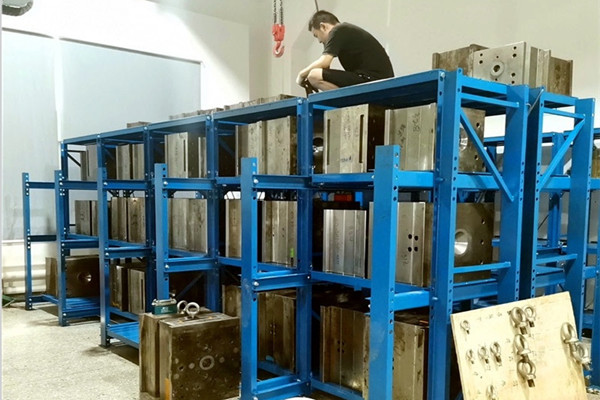 a person using a calculator with a mold rack and a technical drawing in the background
