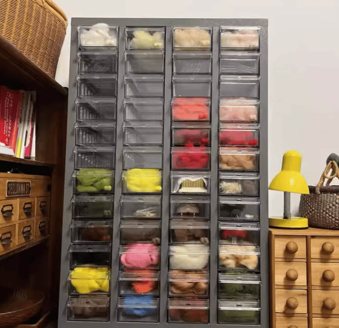 An employee accurately picking a small component from a labeled transparent drawer cabinet.