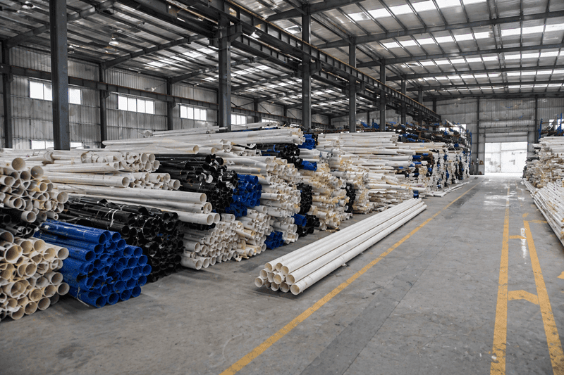 A cluttered warehouse floor with pipes and lumber stacked haphazardly.