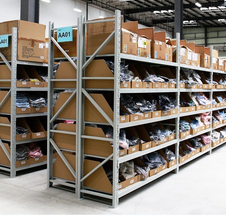 A well-organized warehouse with long span shelving holding various cartons and bins.
