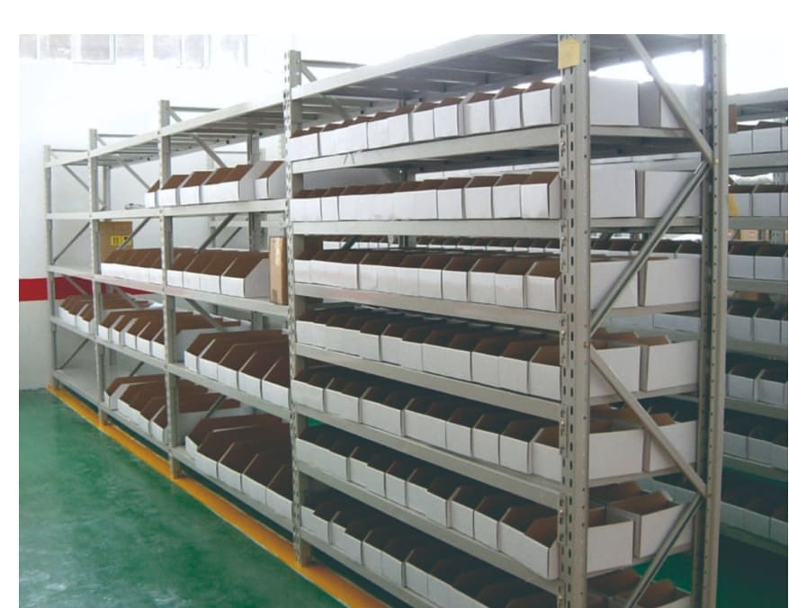 A person using a measuring tape to plan the layout for a new medium duty storage rack in an empty warehouse space.
