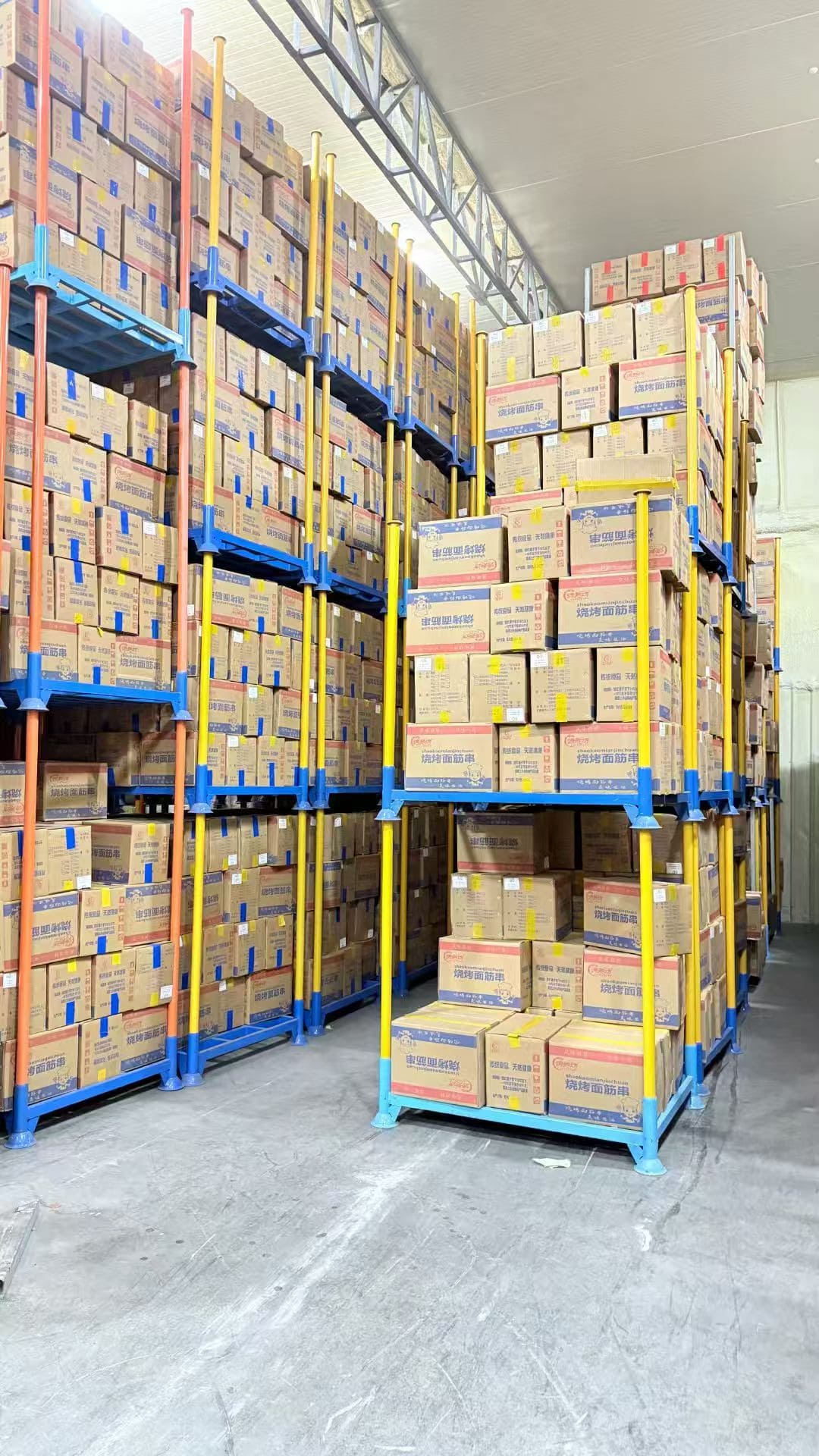 A forklift stacking one portable pallet rack on top of another.