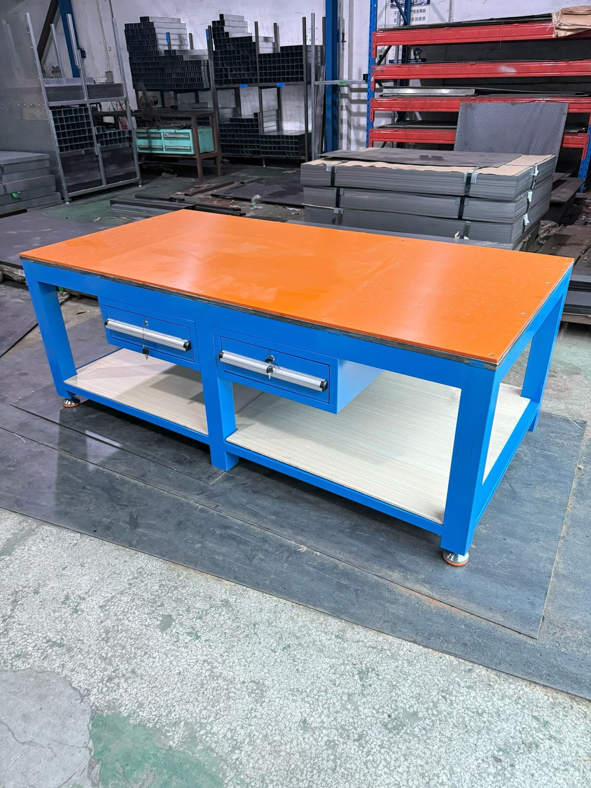 An industrial work table with tool drawers next to a standard wooden workbench.