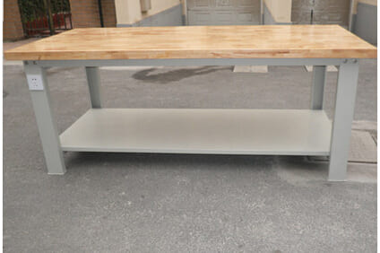 A collapsed standard workbench in a workshop with tools scattered on the floor.
