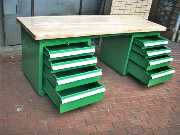 A well-organized industrial workstation with integrated lighting, drawers, and a pegboard.