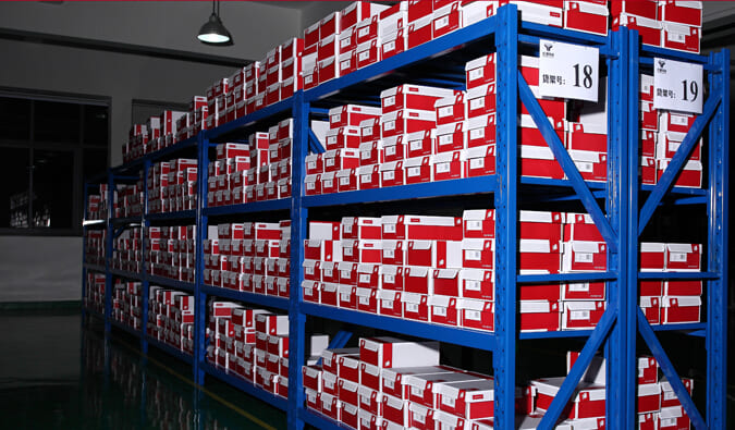 A person using a tape measure to plan the layout for new shelving in a warehouse