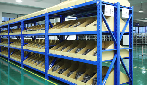 A well-organized warehouse aisle with medium duty shelving holding boxes and parts